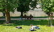 People relax in the green riverside park near the Vltava River, with some lying on the gra...