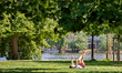 A woman lies on a blanket, raising her legs in the air while relaxing in the shade of ches...