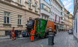 Municipal sanitation workers operate a waste collection truck during garbage pickup in the...