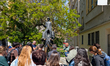 Tourists with a guide stand at the Franz Kafka statue by Jaroslav Rona between the Church...