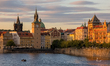 A view of historic buildings along the Vltava River and a swan pedal boat on the water dur...