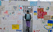 A woman walks through a symbolic wall made of hand-painted peace messages and drawings dur...