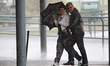 A couple braces against the wind and rain during a short thundershower ahead of the first...