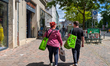 Two people walk in the city carrying green reusable shopping bags from the Asian supermark...
