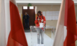 A woman takes a picture with her smartphone as she casts her ballot at a polling station d...