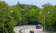 The Expressbus X204 drives along a curved, tree-lined roadway with a church dome visible a...