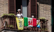 A person assists from the balcony of a house with a flag of yes in favor of the referendum...