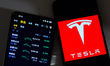The Tesla logo and Tesla's stock price plummet are displayed on mobile phones in Yichang C...