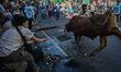 Residents work together to drop a cow during the slaughter of livestock during the Happy E...
