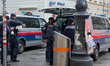 Austrian police officers conduct a visible patrol with multiple police vans in the pedestr...