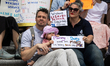 Chris Feddersen (L), Amy Uccello (R) sit with their nine-month-old daughter, Aurelia, with...