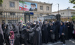 Veiled Iranian women stand in a line under portraits of Iran's late leader, Ayatollah Ruho...