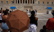 Tourists watch the changing of the Presidential Guard in front of the Hellenic Parliament,...