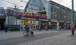 Passengers move through Alexanderplatz Station and the surrounding transit area with visib...