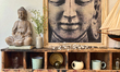 A statue and picture of Lord Buddha are above bowls and cups on a wooden shelf at a shop i...