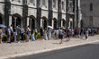 People wait in line using an umbrella near the Monasterio dos Jeronimos during the heat ho...