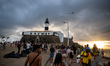 People gather at sunset in front of the Farol da Barra (Barra Lighthouse) in Salvador, Bah...