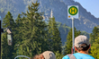Passengers wait at the MVV Bus 996 stop near Neuschwanstein Castle, which is visible in th...
