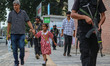 A man and a schoolgirl walk past Indian Security personnel from the Special Operations Gro...