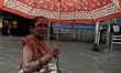 A woman carries an umbrella and wades through a flooded street during heavy monsoon rains...