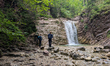 Hikers visit a waterfall at Schleifmuehlklamm near Unterammergau in the Bavarian Ammergau...