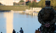 An armed National Guardsman looks out over the reflecting pool fro the steps of the Lincol...