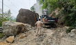 An excavator clears debris after a landslide blocks National Highway 10 in the Kalijhora a...