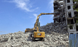 Specialists of a construction company use an excavator with a 40-meter boom to dismantle a...