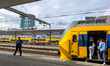 Passengers board yellow and blue NS trains and walk along the platforms at Utrecht Centraa...