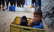 Palestinian children queue for water at a charity distribution point in western Deir al-Ba...