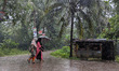 People on the street during monsoon rain in Feni, Bangladesh, on October 2, 2025. As clima...