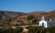 A small blue-and-white chapel stands among olive trees and hills on September 16, 2025, in...