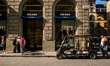A golf cart parks in front of a Prada store on Via Roma in Florence as pedestrians walk th...
