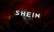 The Shein logo appears on a smartphone screen reflecting an abstract red illustration repr...