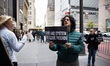 Protesters hold signs and read aloud testimony from Jeffrey Epstein's victims in front of...
