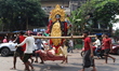 Laborers carry an idol of the Hindu goddess Kali for worship and walk towards a house in a...