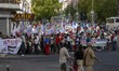 A panoramic view shows a large group of activists and protesters carrying banners, waving...