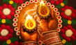A Hindu devotee holds diyas (small decorative clay lamps) by a decorative rangoli design d...