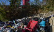 A red stroller surrounded by discarded clothes sits on the outskirts of a city in San Ferd...