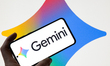 The Gemini logo is displayed on a mobile phone with the company's branding seen in the bac...