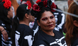 A person with painted face poses for a photo  ahead of the Day of the Dead at Zocalo in Me...