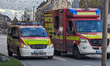 A convoy of emergency vehicles, including fire engines, lines a street with blue flashing...