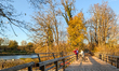 People enjoy a sunny evening with warm autumn sunlight on the wooden Flaucher bridge over...