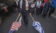 An Iranian man drags the U.S. and Israeli flags along the ground while participating in an...