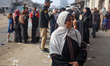 People gather in a line in front of a branch of the Bank of Palestine in Gaza City, on Nov...