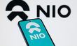 The NIO Ink logo is displayed on a mobile phone with the company branding seen in the back...
