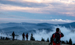 A tourist walks on a mountain slope of Pilska summmit amid picturesque misty views on a mo...