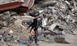 Palestinians walk past an unexploded missile in the Al-Rimal neighborhood of Gaza City, on...