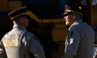 Two Cook County Sheriff's officers speak to each other as construction crews move concrete...