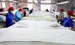 Workers process children's bedding products in a textile and clothing production workshop...